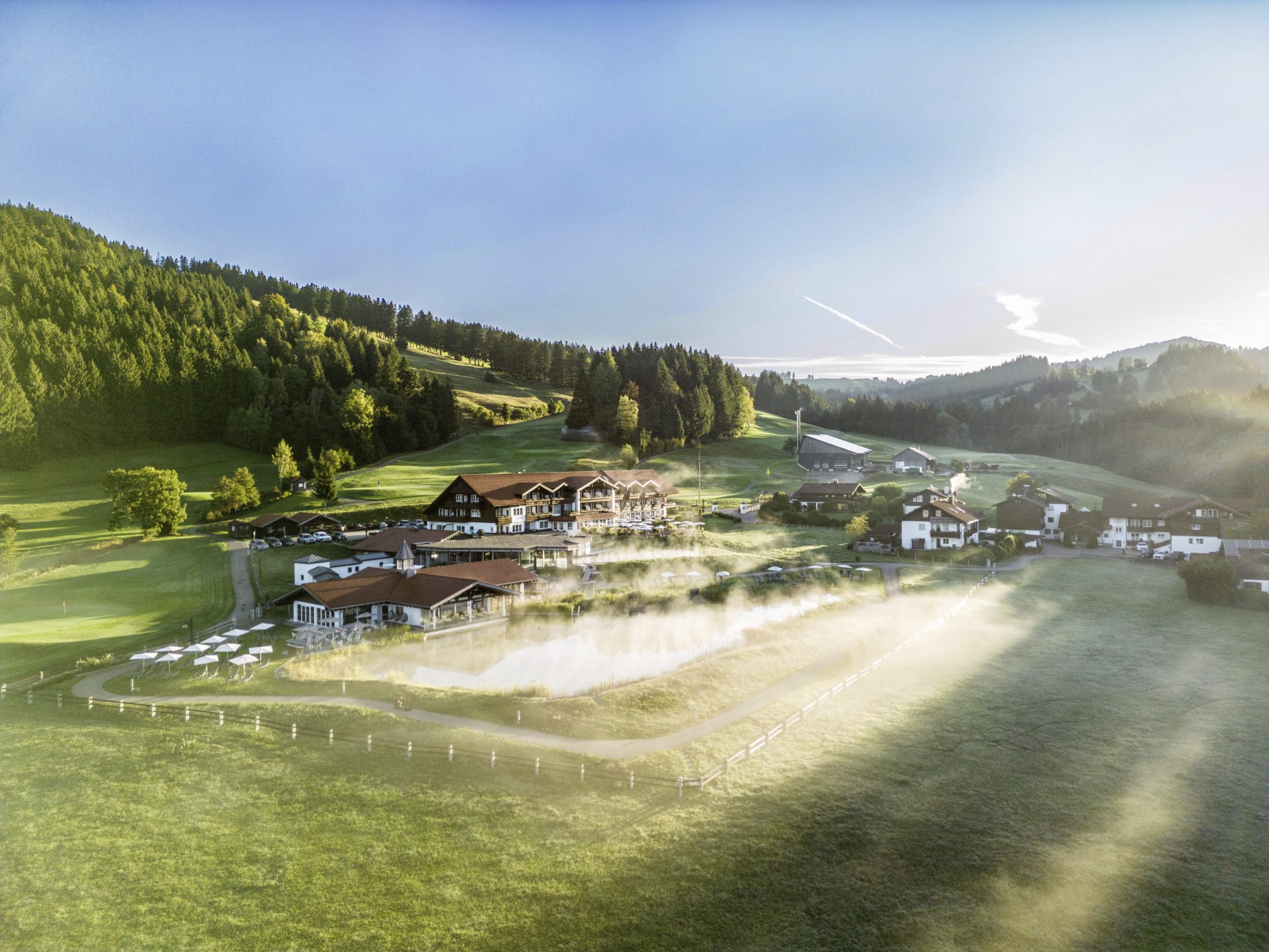 Natursee mit Blick auf das Hotel Haubers Naturresort im Frühnebel