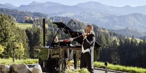 Mann im Frack spielt Geige neben einer Frau am Flügel oben auf dem Berg in Haubers Naturrseort