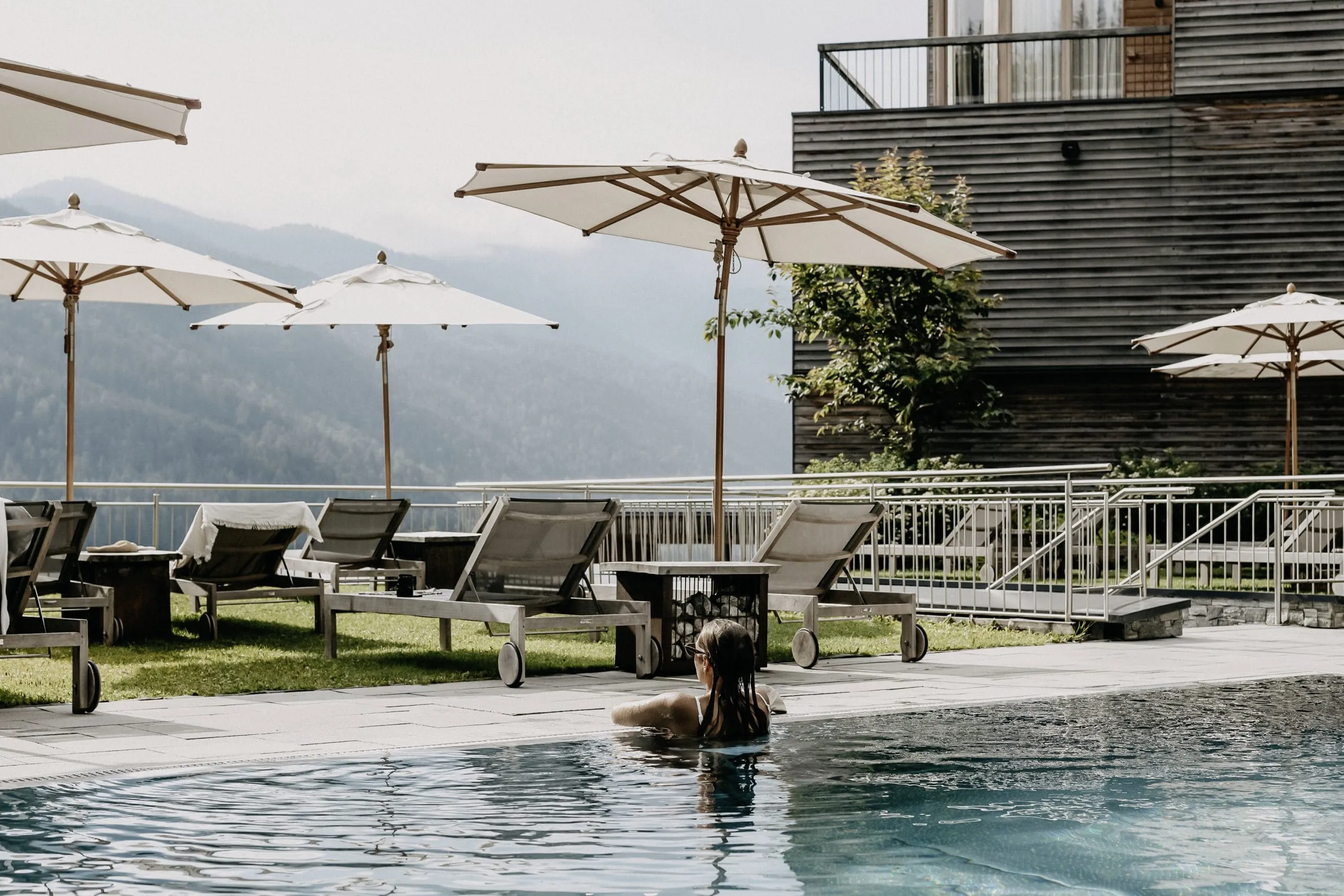 Frau am im Outdoorpool des Das Kronthaler schaut vom Beckenrand auf die Berge