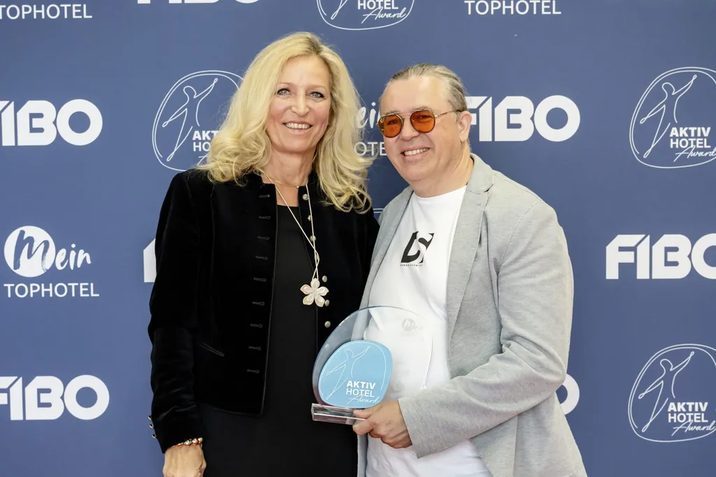 Markus Widauer udn Gattin mit dem Aktiv Hotel Award 2025 vor der FIBO-Fotowand