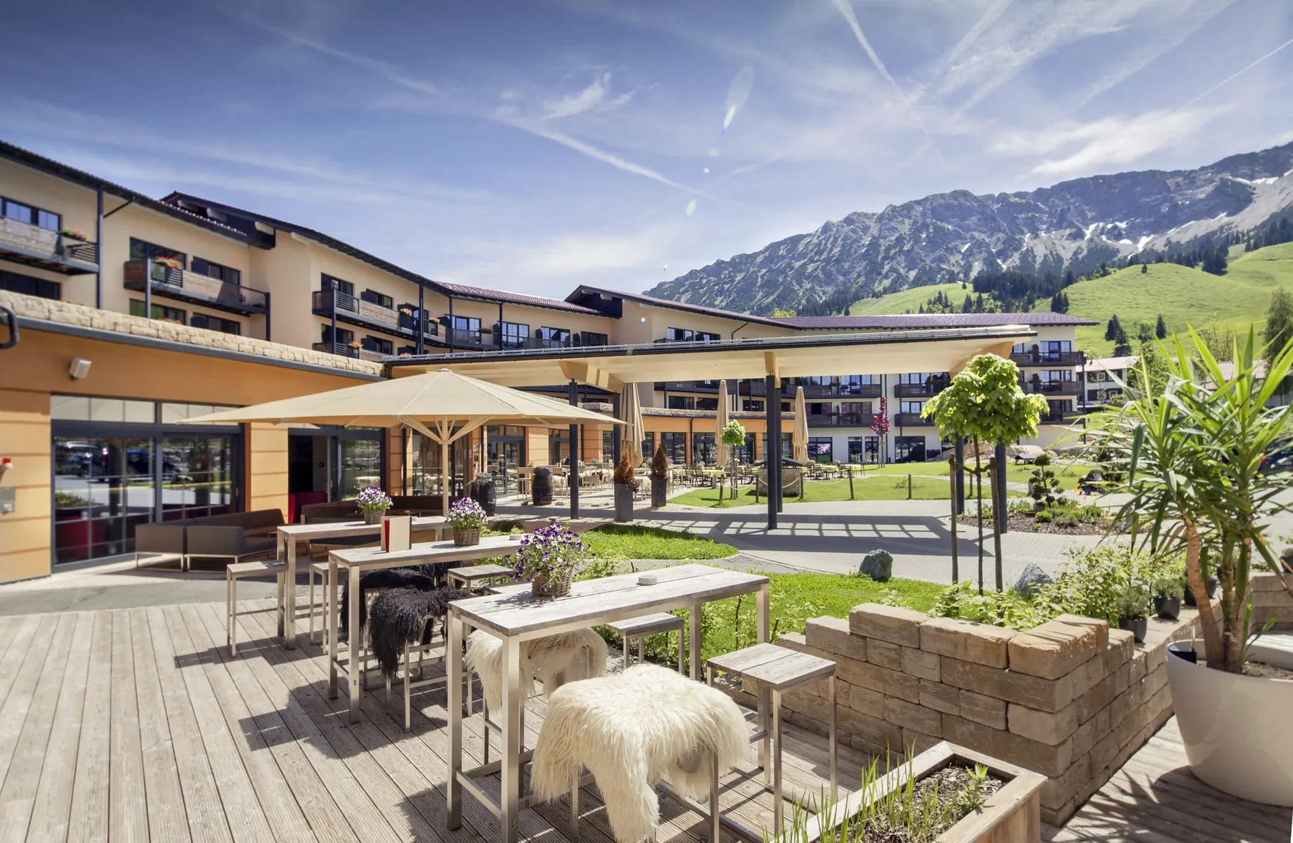 Fassade des Panoramahotel Oberjoch mit Terrasse im Vordergrund und Blick auf die Berge im Sommer