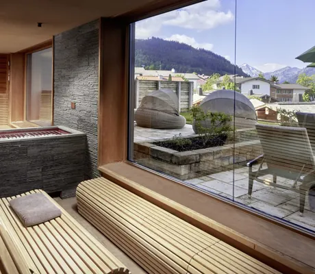 Sauna im Panoramahotel Oberjoch mit abgerundeten Sitzen und Blick auf die Terrasse im Frühling