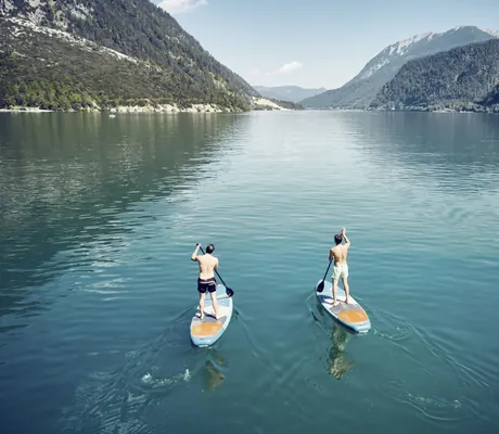 Zwei Männer paddeln auf ihren Stand Up Paddel-Boards auf dem Achensee in der Nähe des Travel Charme Fürstenhaus