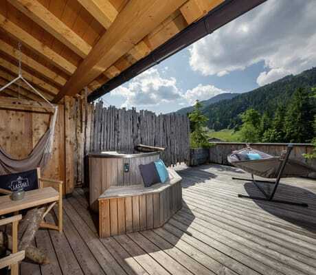 Holzterrasse mit Hängesessel, Hot Tub, Liege und Alpenblick bei sonnigem Bergwetter im mama thresl