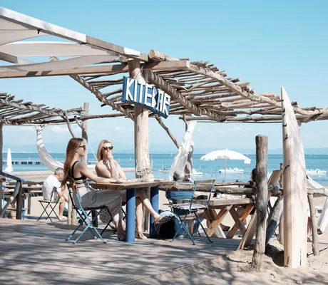 Zwei Frauen sitzen in der Kitebar direkt am Strand mit Blick auf das Meer in unmittelbarer Nähe des Tenuta Primero Grado Family Collection