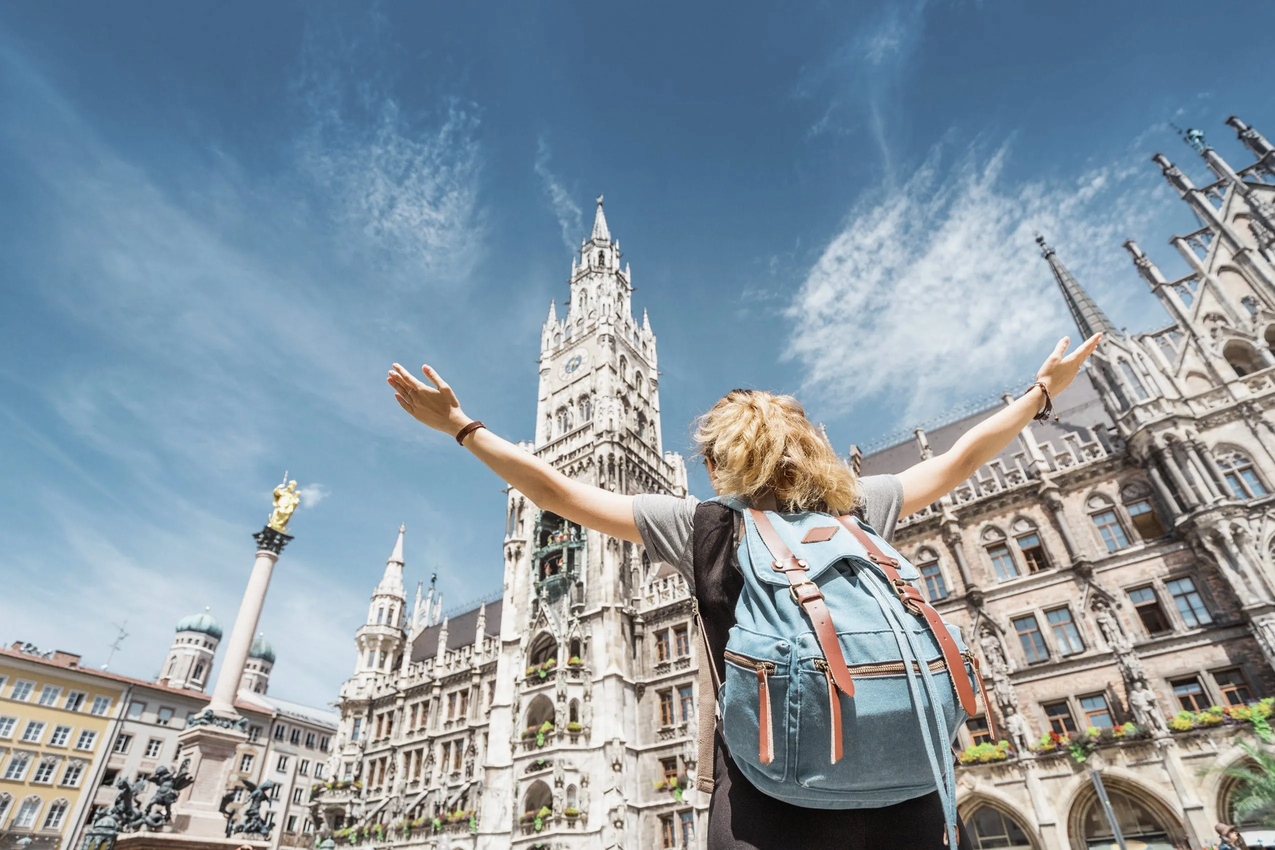 Junge Frau mit Rucksack steckt auf dem Marienplatz in München und blickt Richtung Glockenturm