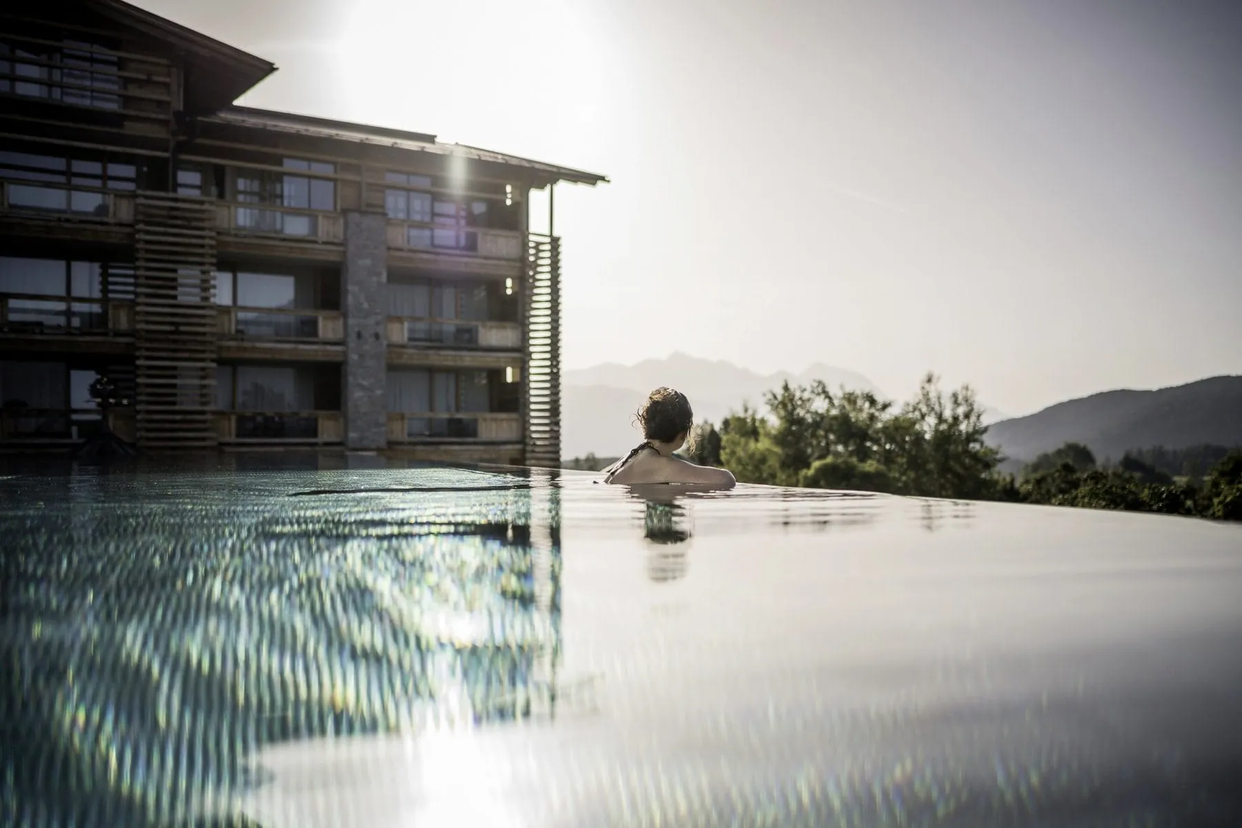 Frau lehnt sich über den Beckenrand des Outdoorpools im Alpenresort Schwarz