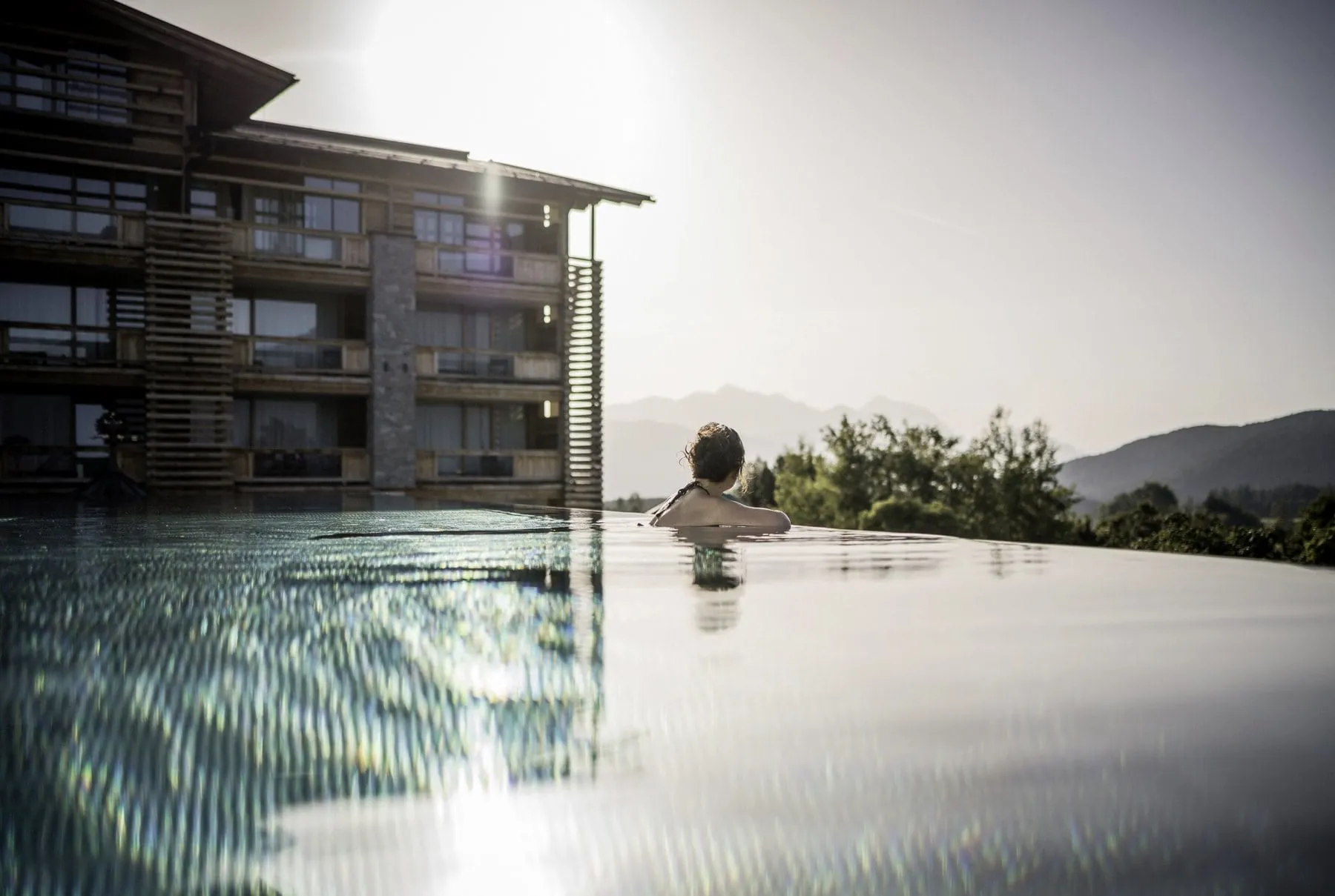 Frau lehnt sich über den Beckenrand des Outdoorpools im Alpenresort Schwarz