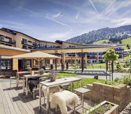 Fassade des Panoramahotel Oberjoch mit Terrasse im Vordergrund und Blick auf die Berge im Sommer