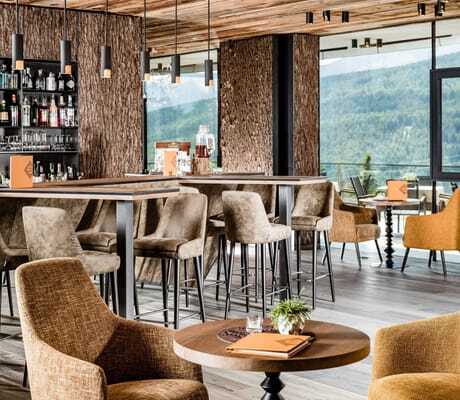 Stylische Bar des SONNENBERG | Panorama Dolomites Wellbeing mit Samt-Barhockern und großen Panoramafenstern