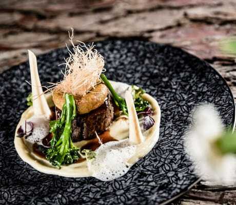 Fleisch-Gourmetgericht des SONNENBERG | Panorama Dolomites Wellbeing auf dunkel, gemustertem Teller