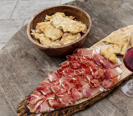 Brotzeitplatte mit Südtiroler Speck und Schüttelbrot neben zwei Gläsern Rotwein im Das Parkhotel