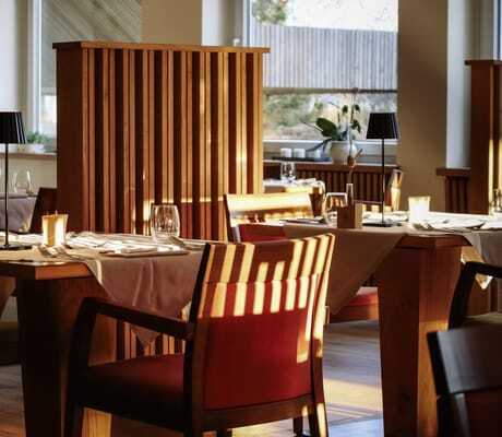 eingedeckte Tische zwischen Holztrennwänden im Restaurant des Das Parkhotel