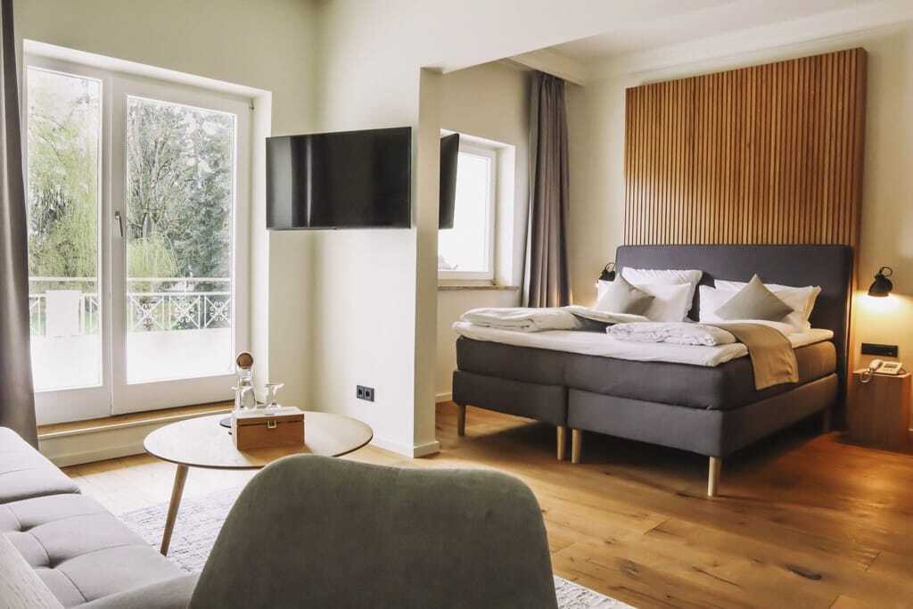 Doppelzimmer mit Lamellen-Holzrückwand am Bett und Balkon im Das Parkhotel