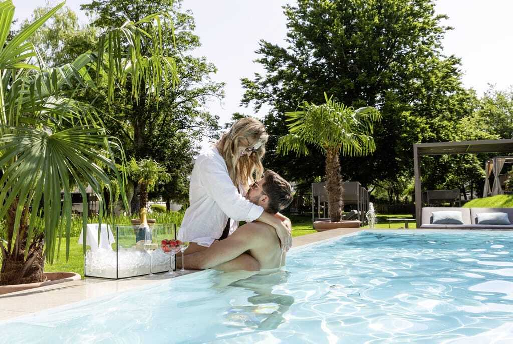 Paar umarmt sich am Beckenrand des Infinity-Outdoorpools im Das Parkhotel