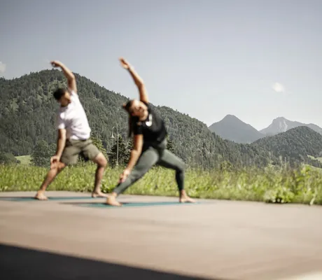 Mann und Frau machen Yoga in der Gartenanlage des Peternhof Wohlfühlresort
