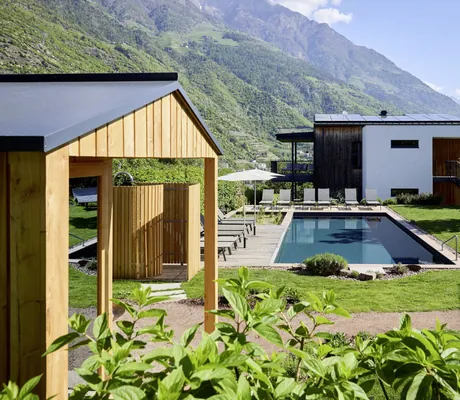 Moderner Poolbereich der Cirna Gentle Luxury Lodges mit Liegestühlen und einer Außendusche vor dem Hintergrund einer imposanten Berglandschaft