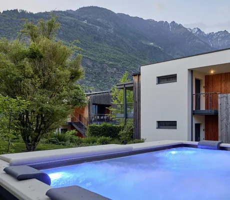 Beleuchteter Edelstahl-Whirlpool mit gepolstertem Rand im Garten der Cirna Gentle Luxury Lodges bei Abenddämmerung