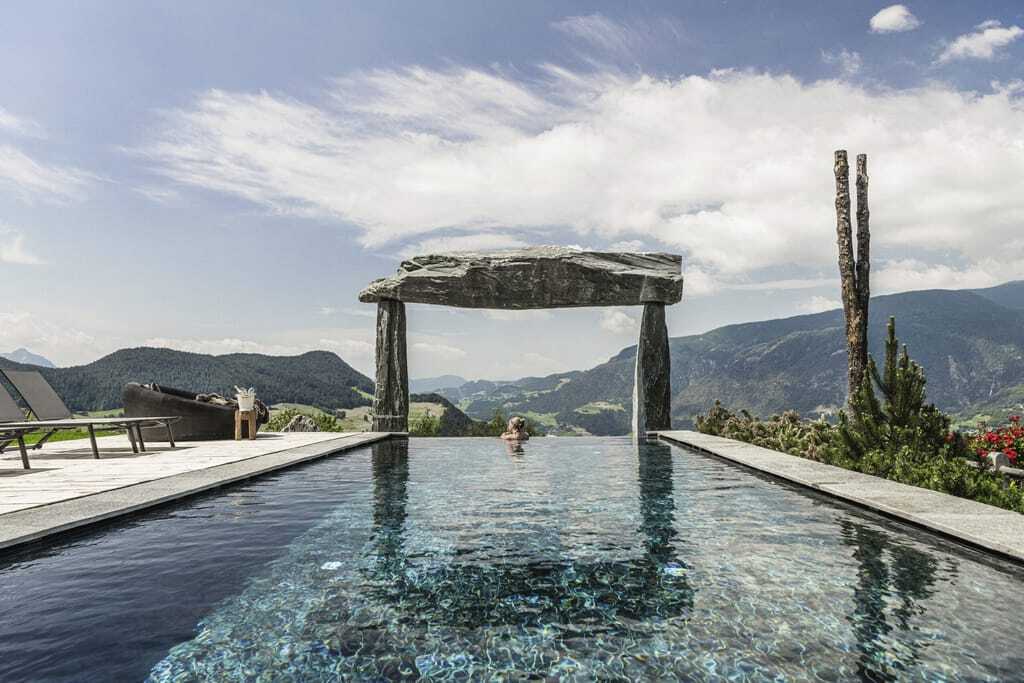 Junge Frau am Ende des Outdoor-Infinitypools im Chalet Resort ZU KIRCHWIES