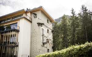 Blick auf die Fassade des Excelsior Dolomites Life Resort mit Kletterwand