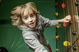 Junge an der Kletterwand in der Spielscheune des Familotel Elldus Resort
