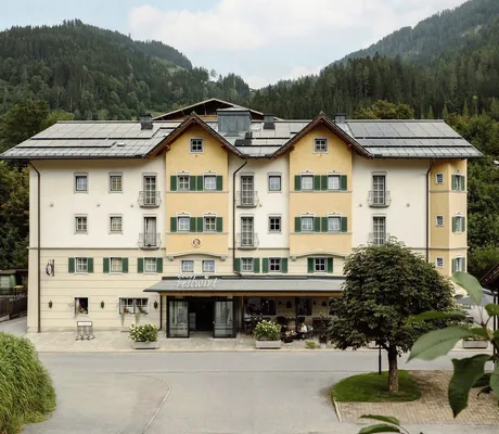 Fassade des Resl Resort im traditionellen Stil, eingebettet in eine malerische Berglandschaft und Kirche im Hintergrund