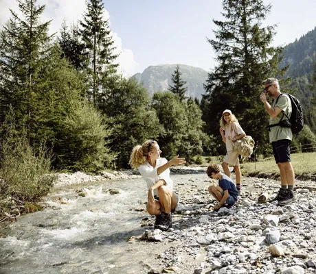 Familie in Wanderbekleidung macht eine Pause an einem kleinen Bach in der Nähe des Resl Resort