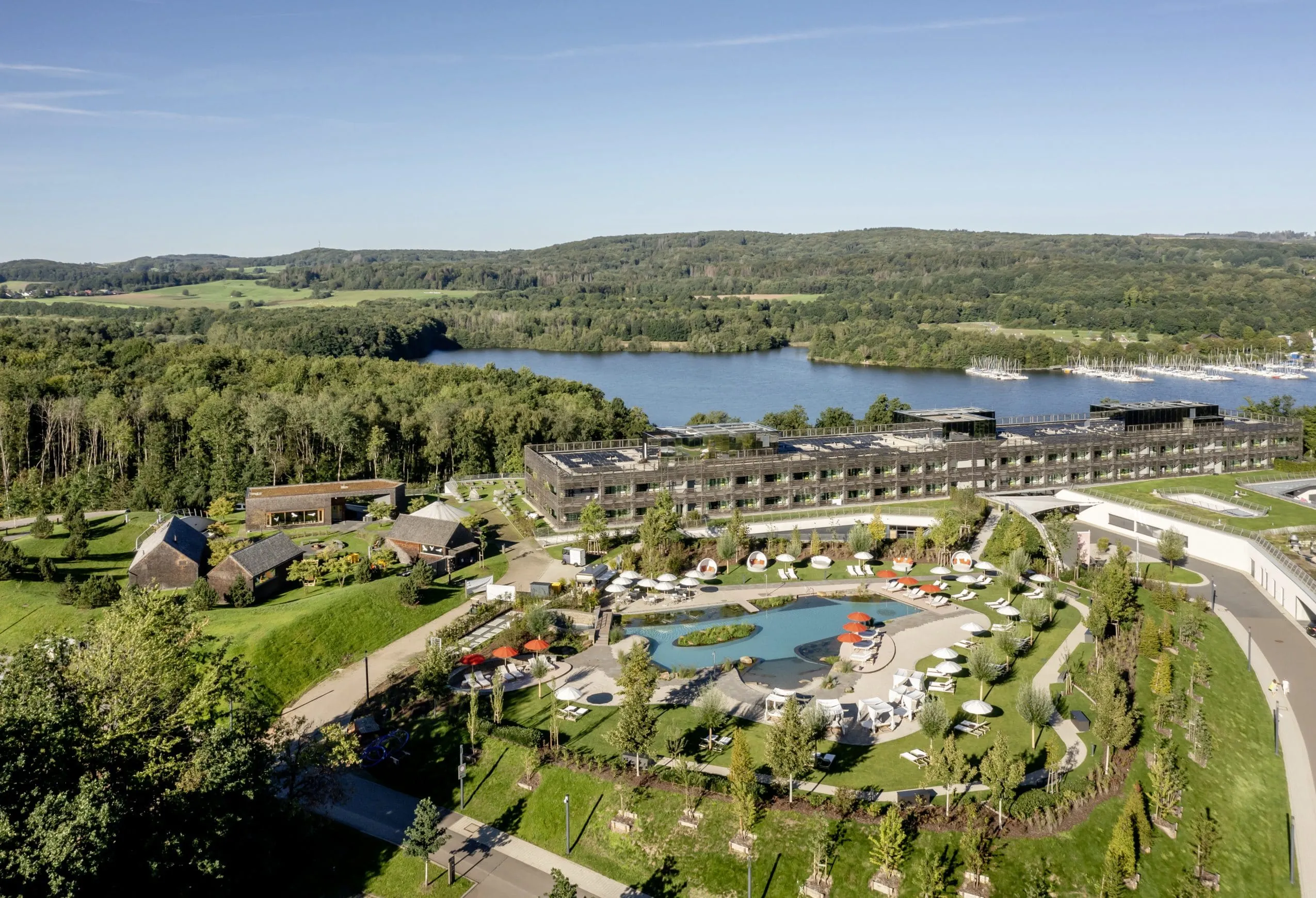 Luftaufnahme der Seezeitlodge mit Poolanlage, direkt am See gelegen, umgeben von Waldlandschaft