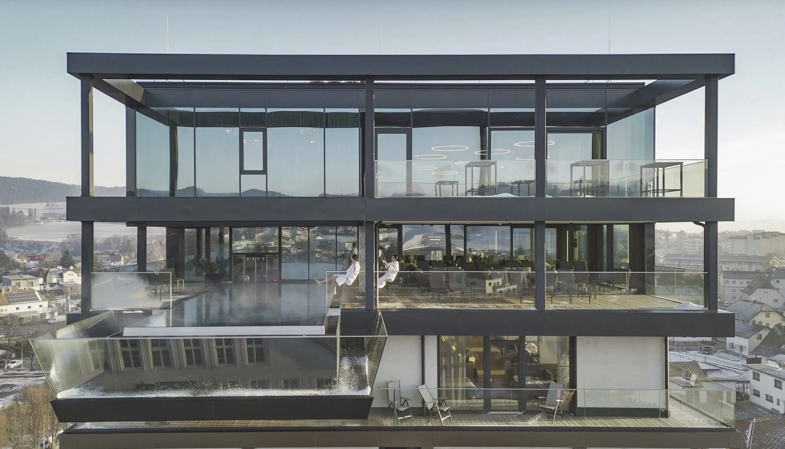 Paar in weißen Bademänteln schaukelt über dem Sky-Pool des Impulshotel FREIGOLD