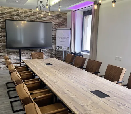 Boardingroom mit langem Holztisch und großem Monitor im Parkhotel Schillerhain