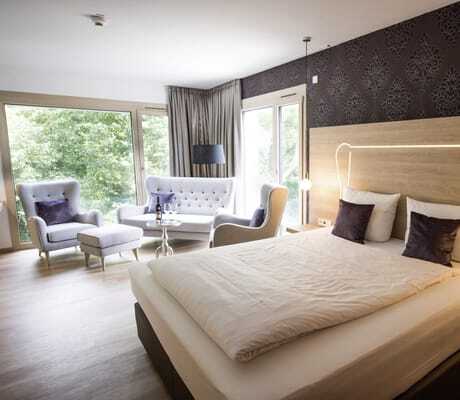 Doppelzimmer mit beleuchtetem Bettkopf und Loungemöbeln im Parkhotel Schillerhain