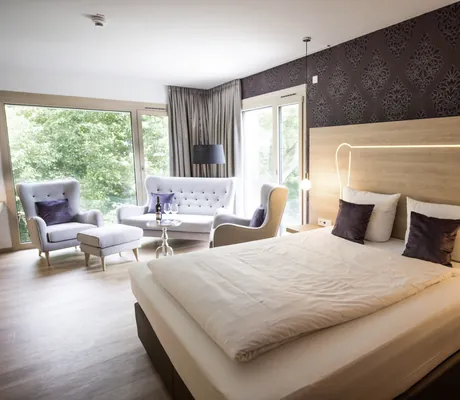 Doppelzimmer mit beleuchtetem Bettkopf und Loungemöbeln im Parkhotel Schillerhain