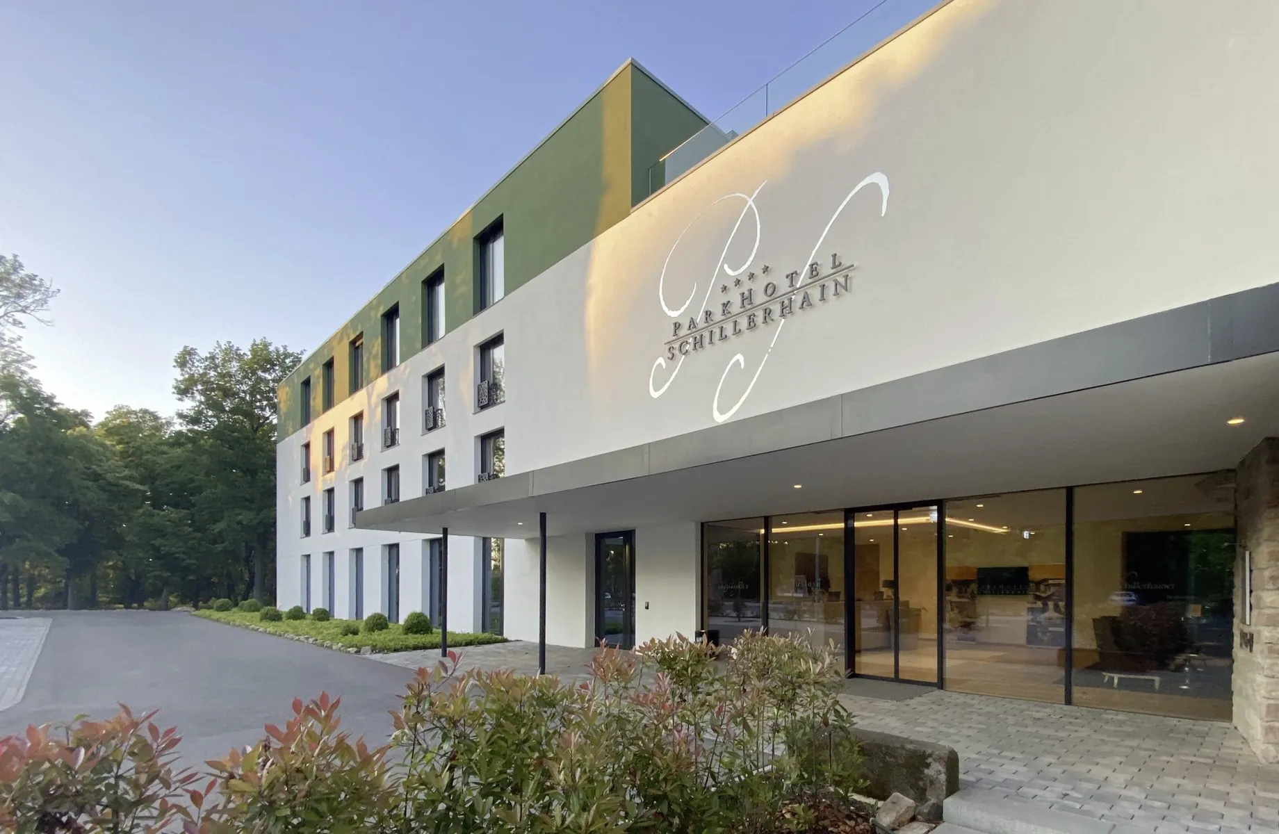 moderner Eingangsbereich des Parkhotel Schillerhain mit Schriftzug auf der Fassade