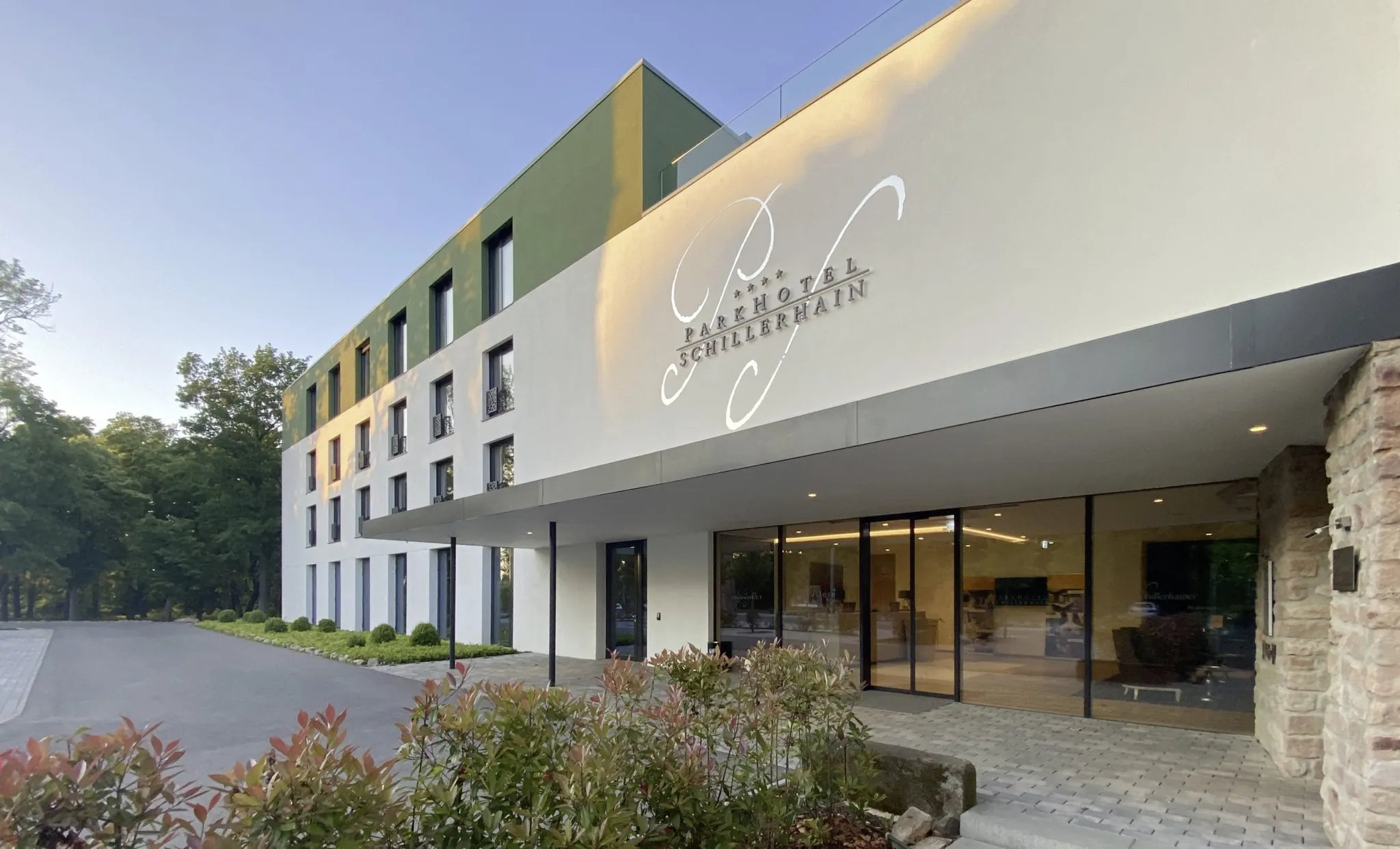 moderner Eingangsbereich des Parkhotel Schillerhain mit Schriftzug auf der Fassade