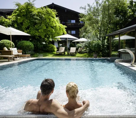 Pärchen auf Sprudelliegen im Outdoorpool des Der Böglerhof – pure nature spa resort