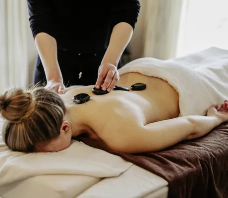 Frau liegt auf einer Massageliege und bekommt eine Hot Stone-Massage im Wellnesshotel Randsbergerhof