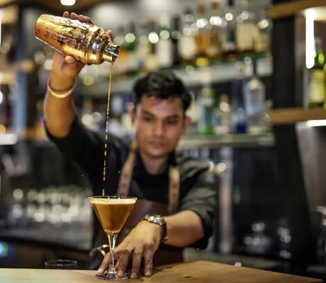 Barkeeper des Wellnesshotel Randsbergerhof gießt einen Espresso Martini vom Cocktailshaker in ein Martini-Glas