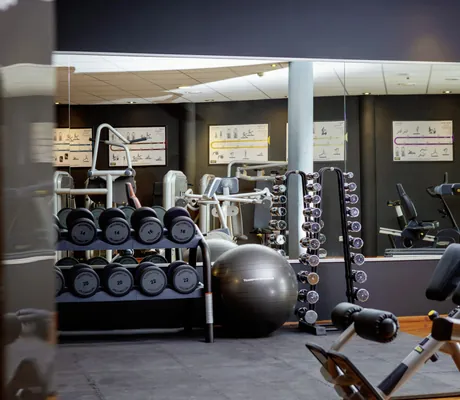 Blick in das Fitnessstudio des Wellness- und Naturresort Reischlhof mit Geräten, Hanteln und Gymnastikball
