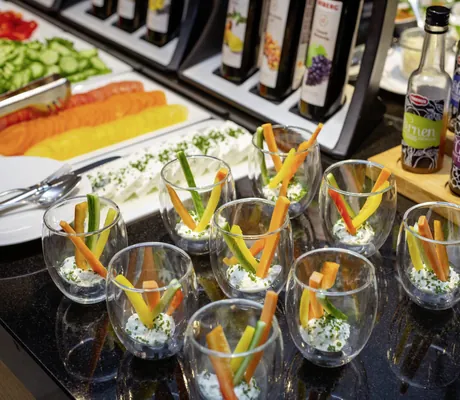 Mehrere kleine Gläser mit Frischkäse, garniert mit Karotten-, Gurken- und Paprikasticks, geschnittenes Gemüse und mehrere Flaschen Essig im Hintergrund im Wellness- und Naturresort Reischlhof