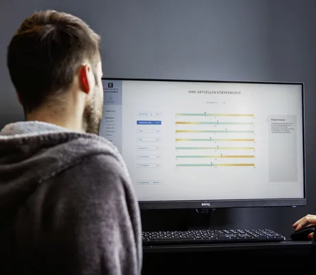 Mann und Frau schauen auf einen Bildschirm, der die Auswertung eines Körperscans im Wellness- und Naturresort Reischlhof zeigt