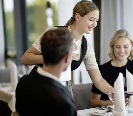 Bedienung des Wellness- und Naturresort Reischlhof serviert einem Paar Rotwein