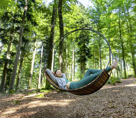 Frau liegt in Hängeschaukel aus Holz im WaldSpa des Wellness- und Naturresort Reischlhof