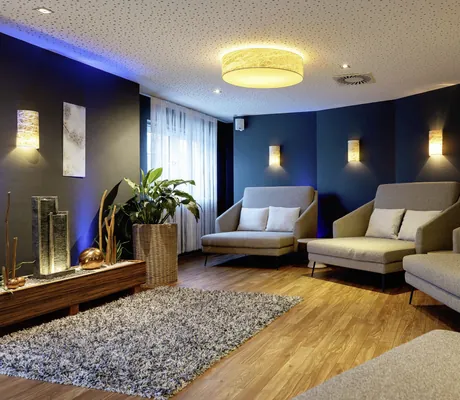 Gemütlicher Wasser-Ruheraum des Wellness- und Naturresort Reischlhof mit mehreren Sofaliegen und Holzboden mit grauem Teppich