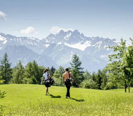 Panoramablick auf zwei Golfspieler vor majestätischer Alpenkulisse in unmittelbarer Nähe des Sonnenalp Resorts