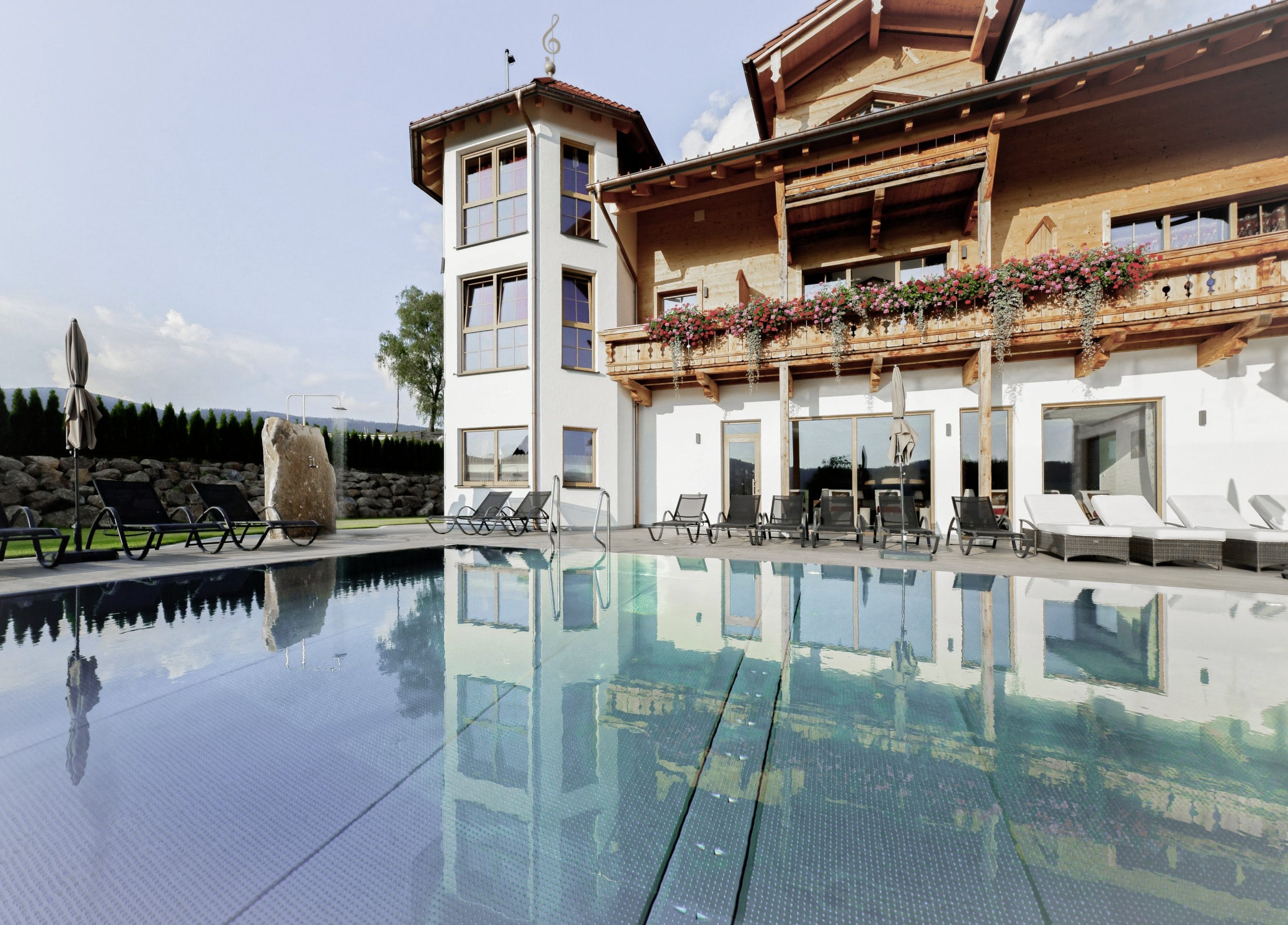 Rustikale Hotelfassade des Wellness & Naturhotel Tonihof****S mit Outdoorpool im Vordergrund
