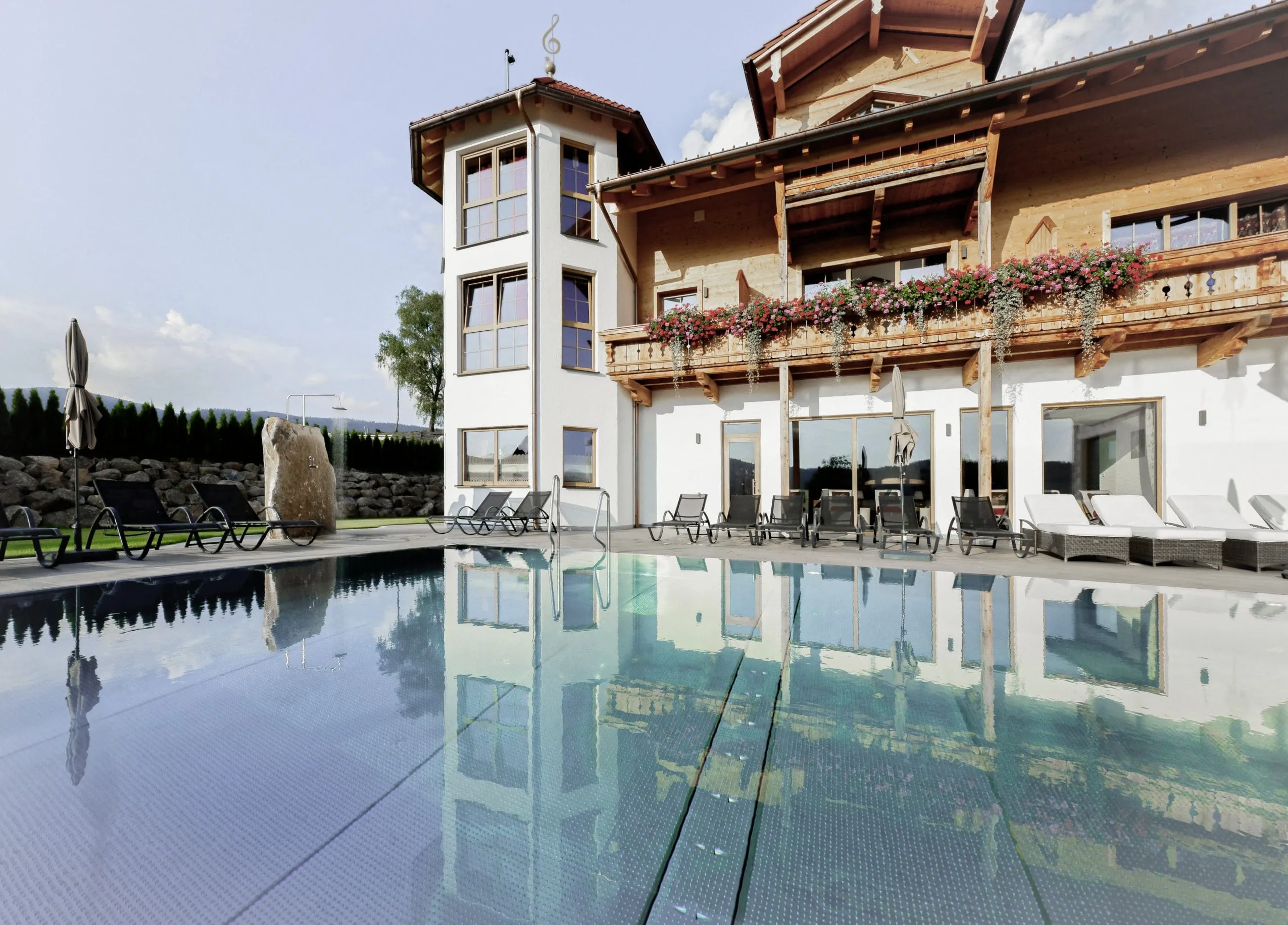 Rustikale Hotelfassade des Wellness & Naturhotel Tonihof****S mit Outdoorpool im Vordergrund