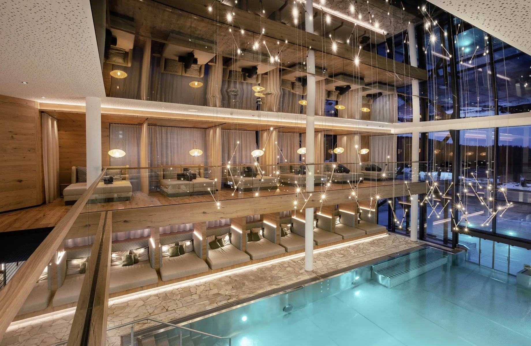 Eleganter Spa-Bereich mit türkis beleuchtetem Indoorpool, stilvollen Liegen und moderner Lichtinstallation bei Abendstimmung im Wellness & Naturhotel Tonihof****S