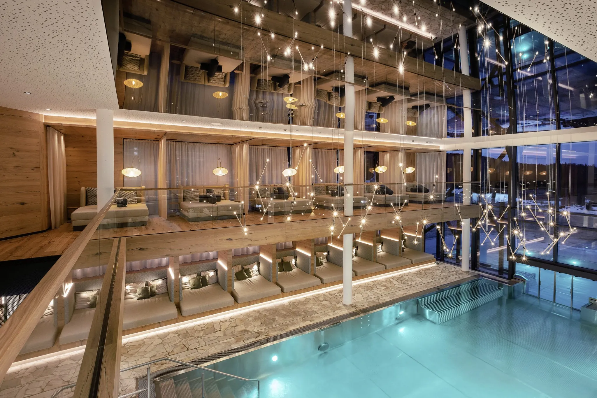 Eleganter Spa-Bereich mit türkis beleuchtetem Indoorpool, stilvollen Liegen und moderner Lichtinstallation bei Abendstimmung im Wellness & Naturhotel Tonihof****S