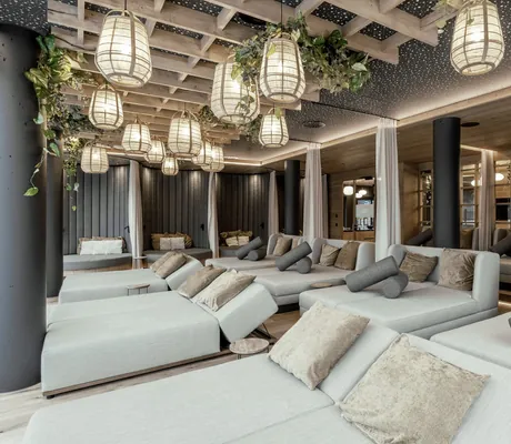 Hellgraue Ruheliegen mit Kissen im Wellnessbereich des Wellness & Naturhotel Tonihof****S, Holzgitter mit Hängelampen und Pflanzen an der Decke