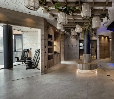 Blick in den modernen Saunabereich des Wellness & Naturhotel Tonihof****S mit runder Sitzmöglichkeit, Hängelampen, Holzdekor und Pflanzen